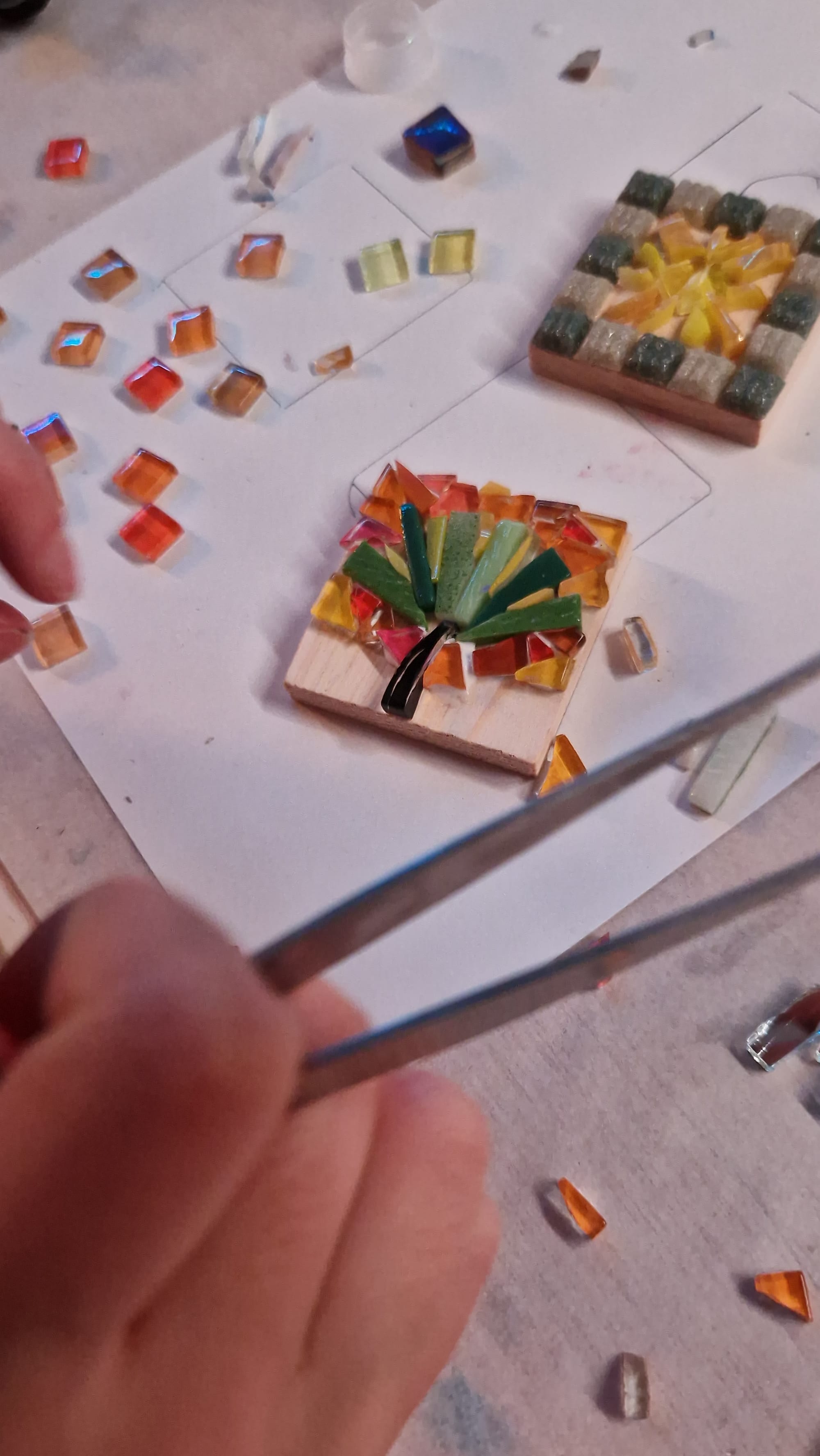 Mains et pince au-dessus d’une mosaïque colorée en cours
