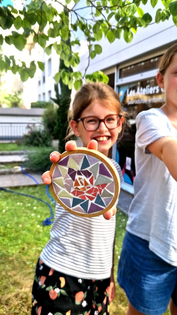 Enfant présentant un dessous de verre mosaïque géométrique